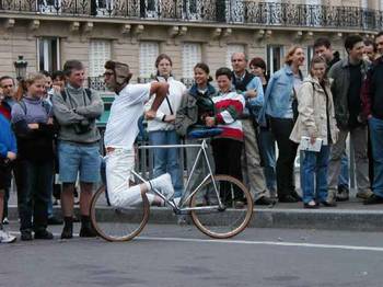 Bicyclist pedals backwards while riding in front of handlebars.